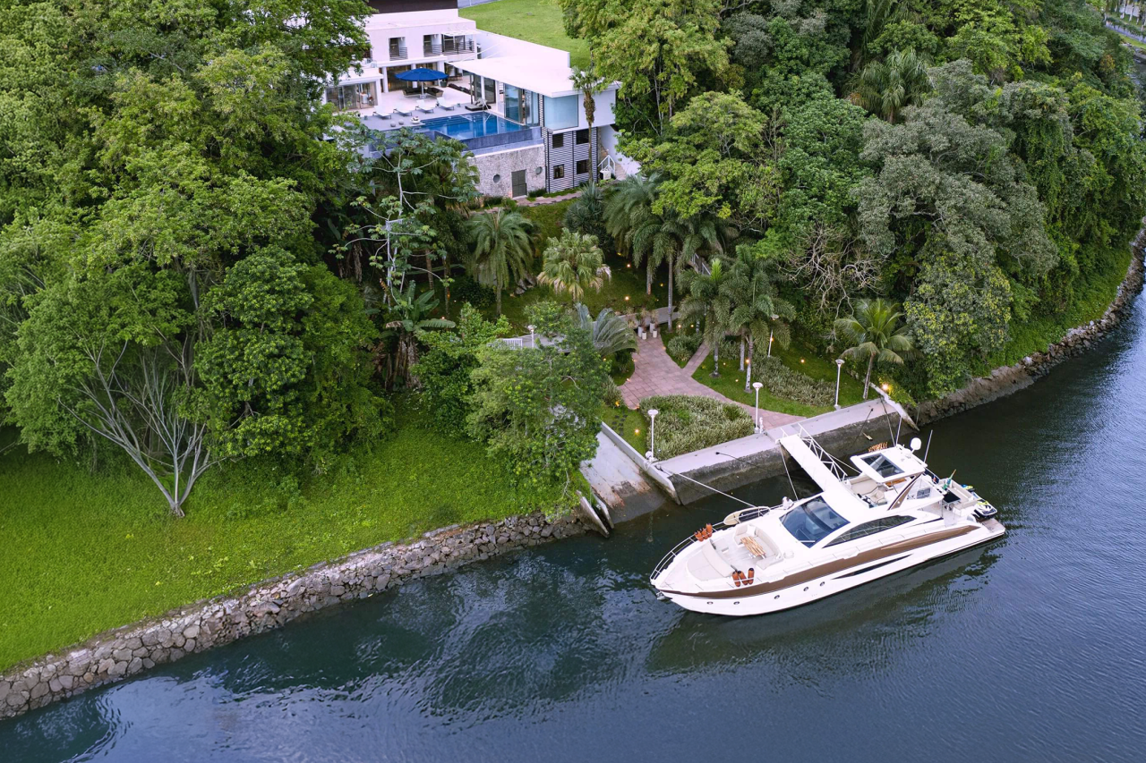 Real Estate Duo: casa à beira-mar (mobiliada) + barco de 78 pés no píer. Dois universos de luxo se encontram no litoral paulista.